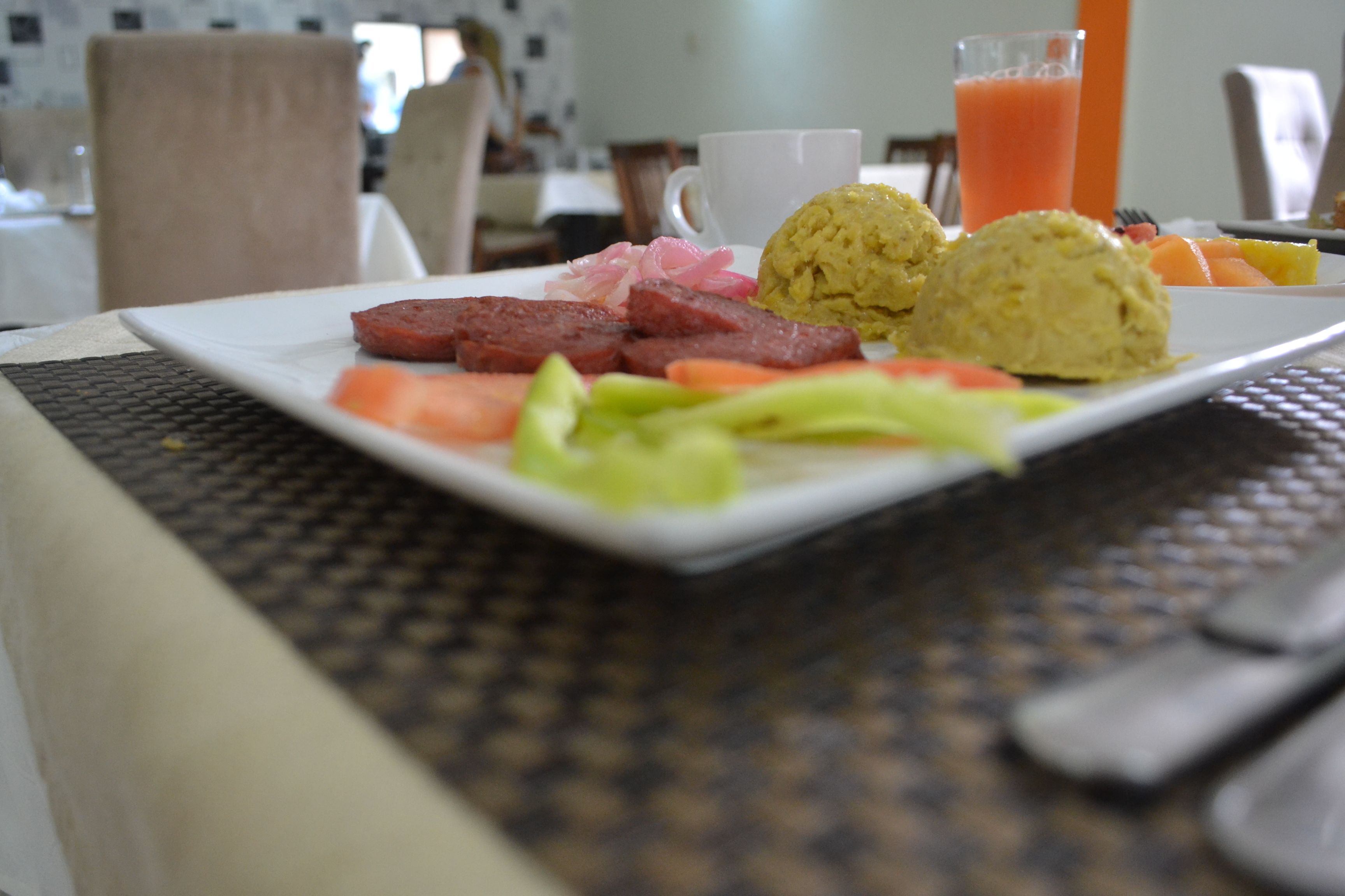 A breakfast plate with eggs, sausage, tomatoes, and a glass of orange juice.