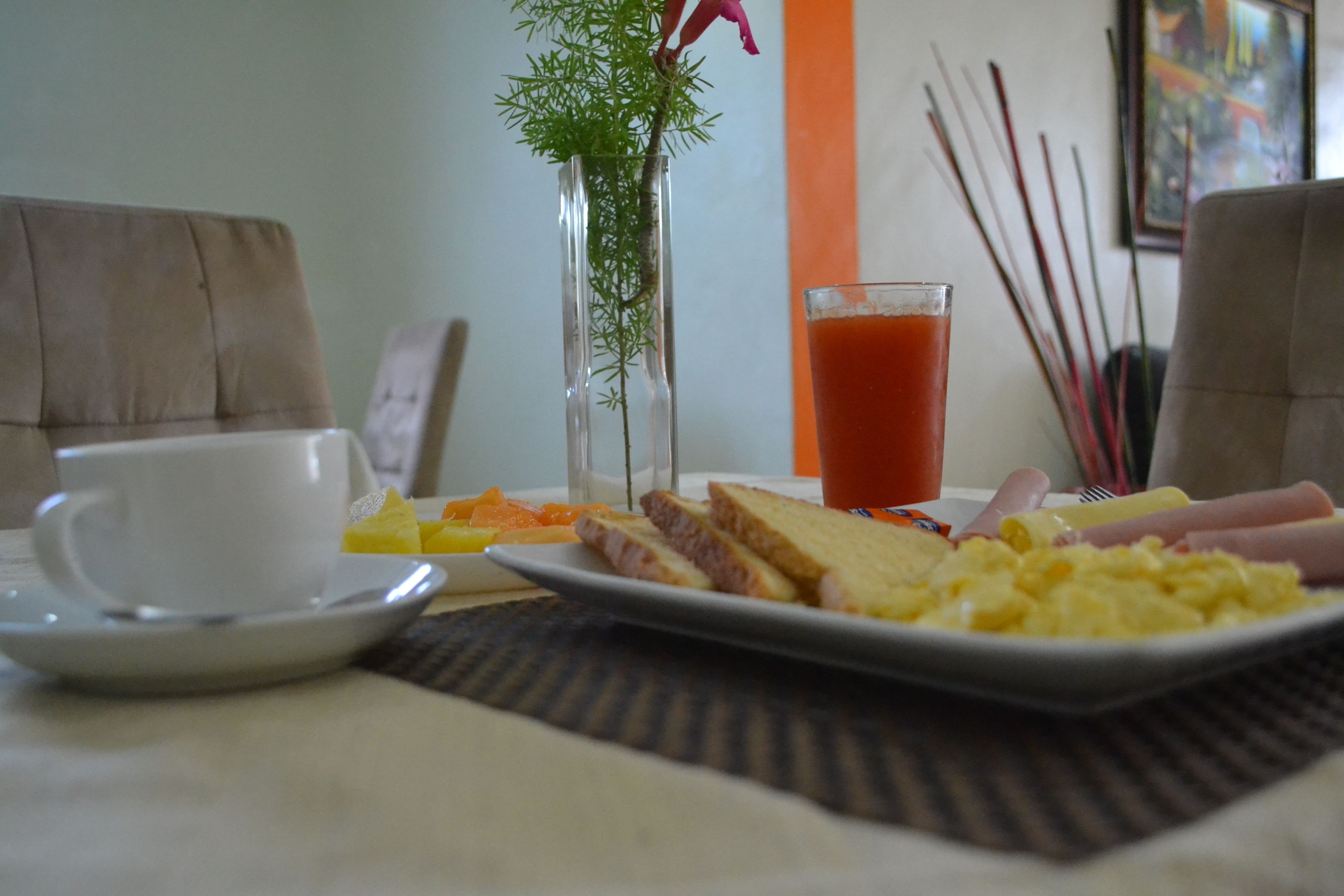 A breakfast setting with a plate of food, a glass of juice, and a cup on a table.