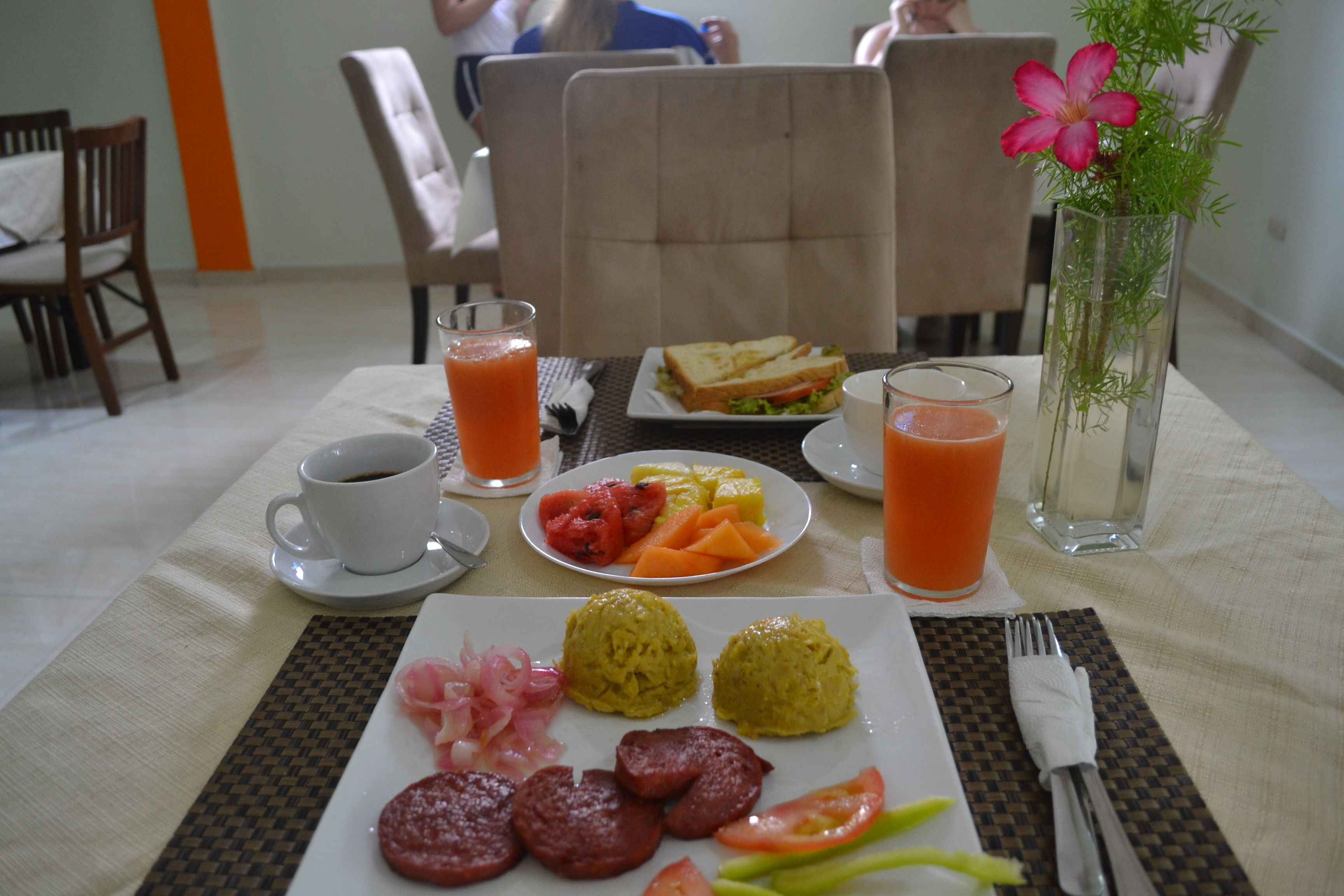 A breakfast table with plates of food, a cup of coffee, and a glass of orange juice.