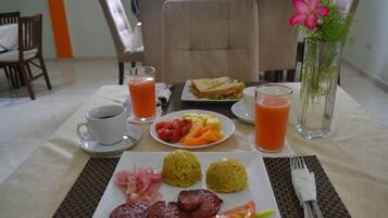 Una mesa de desayuno con platos de comida, una taza de café y un vaso de zumo de naranja.