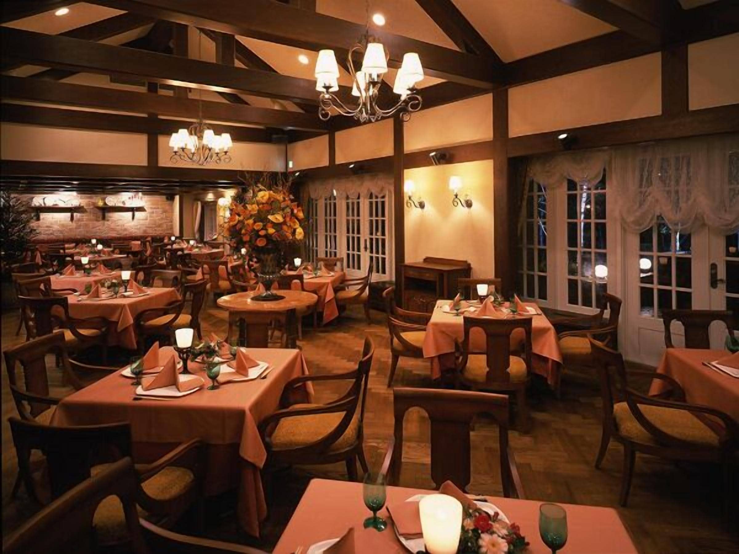 Un restaurante con varias mesas y sillas, iluminación cálida y un candelabro.