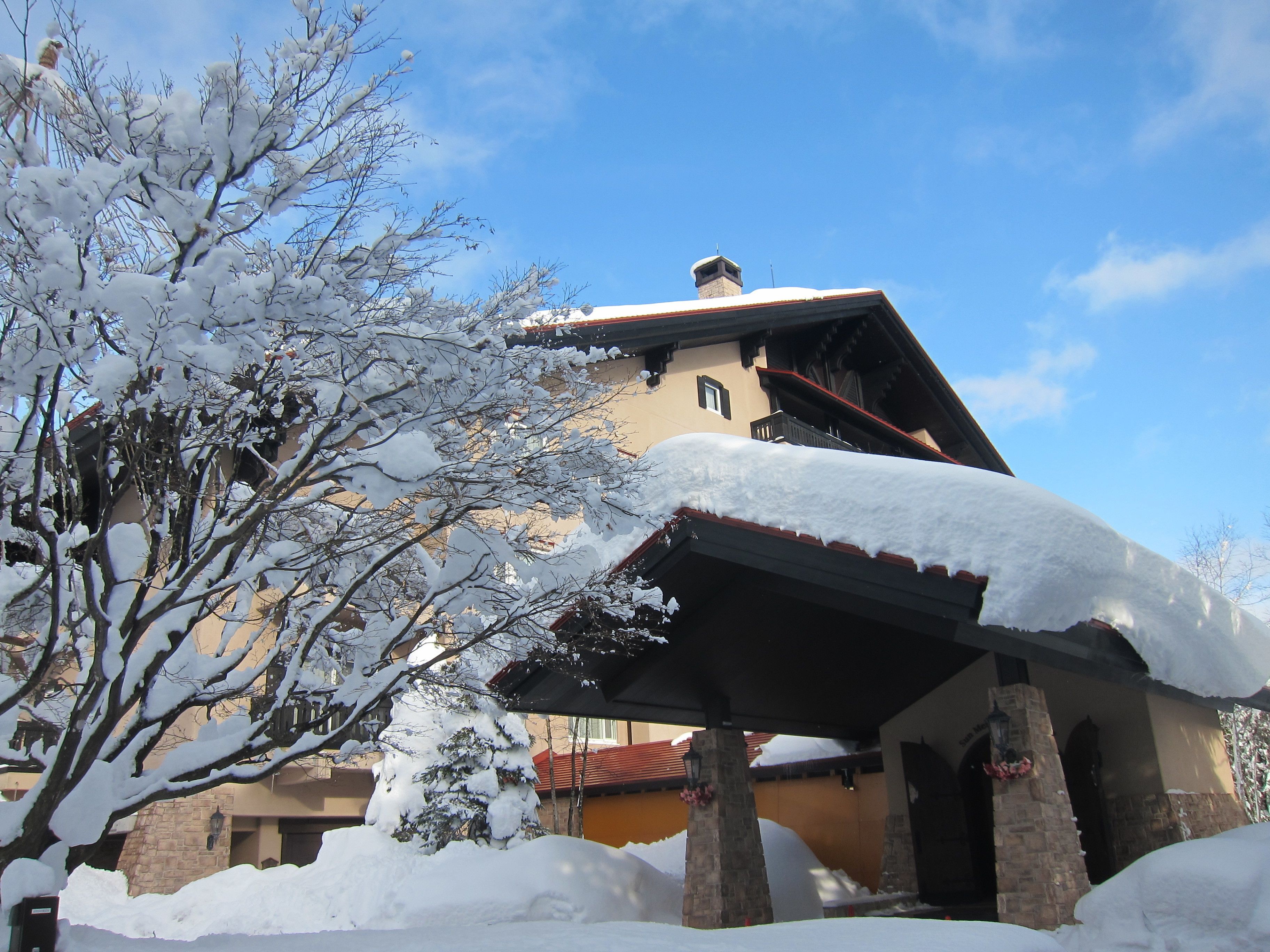 A building with a snow-covered roof and a stone chimney.
