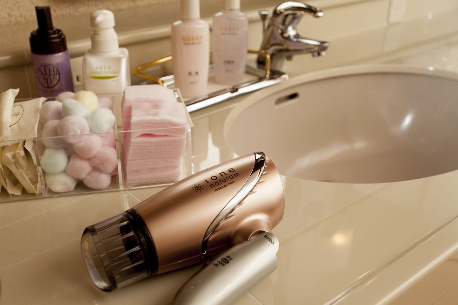 A bathroom with a sink, toiletries, and a hairdryer.