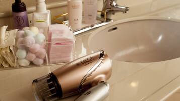 A bathroom with a sink, toiletries, and a hairdryer.