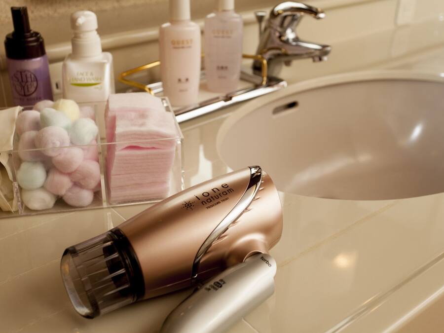 A bathroom with a sink, toiletries, and a hairdryer.