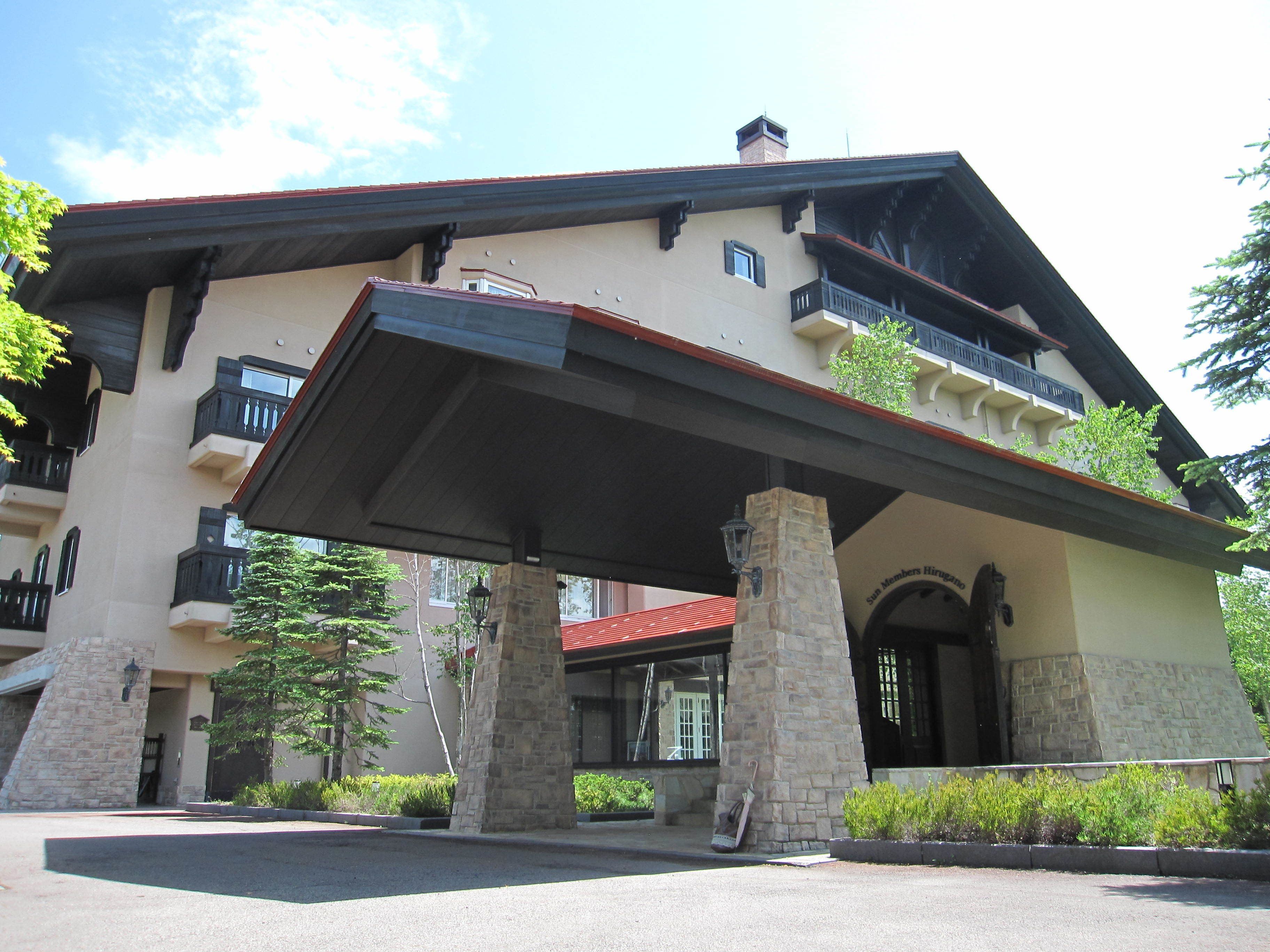 A multi-story building with a stone facade, balconies, and a covered entrance area.