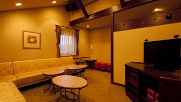 A cozy living room with a sofa, two small tables, a television, and a fireplace.
