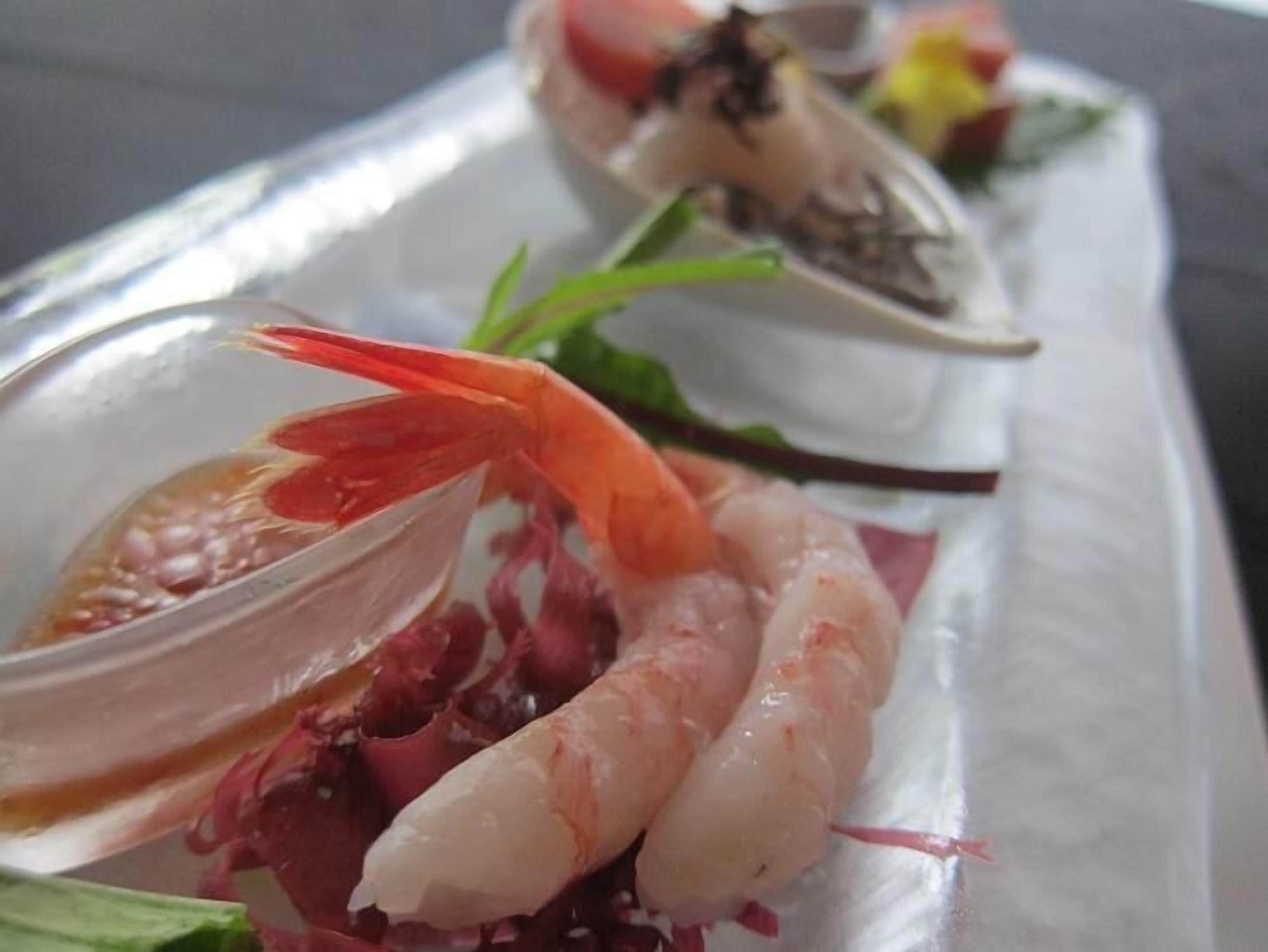 Ein Fischgericht mit Garnelen, Jakobsmuscheln und einer roten Paprika-Garnitur.