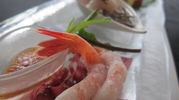 Ein Fischgericht mit Garnelen, Jakobsmuscheln und einer roten Paprika-Garnitur.