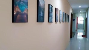 Un couloir orné d’une série de tableaux encadrés accrochés au mur, un sol impeccable et un plafond doté d’un éclairage encastré.