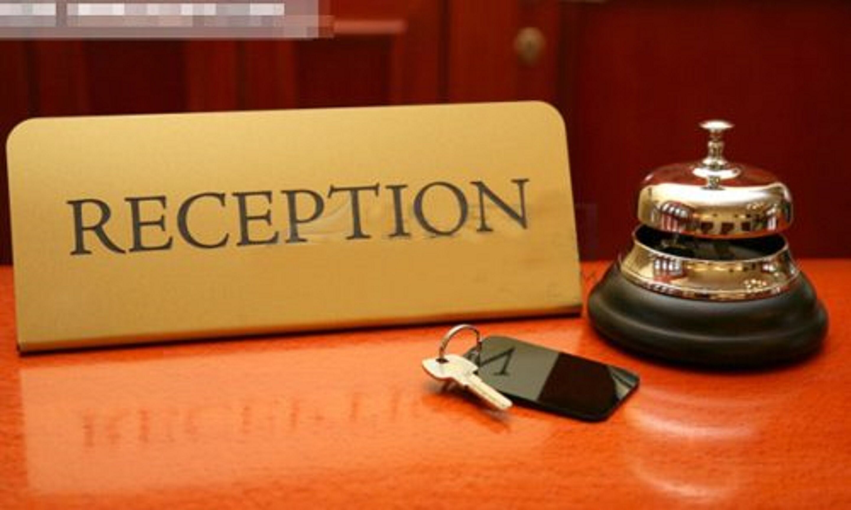 A reception sign with a bell and a key on a wooden surface.