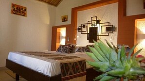 A bedroom with a bed, a wall-mounted artwork, and a plant.