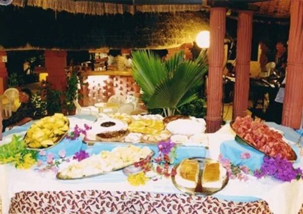 A buffet table with various food items and a decorative palm tree. - Hôtel Les Bougainvillées Saly Sénégal (Mbour)