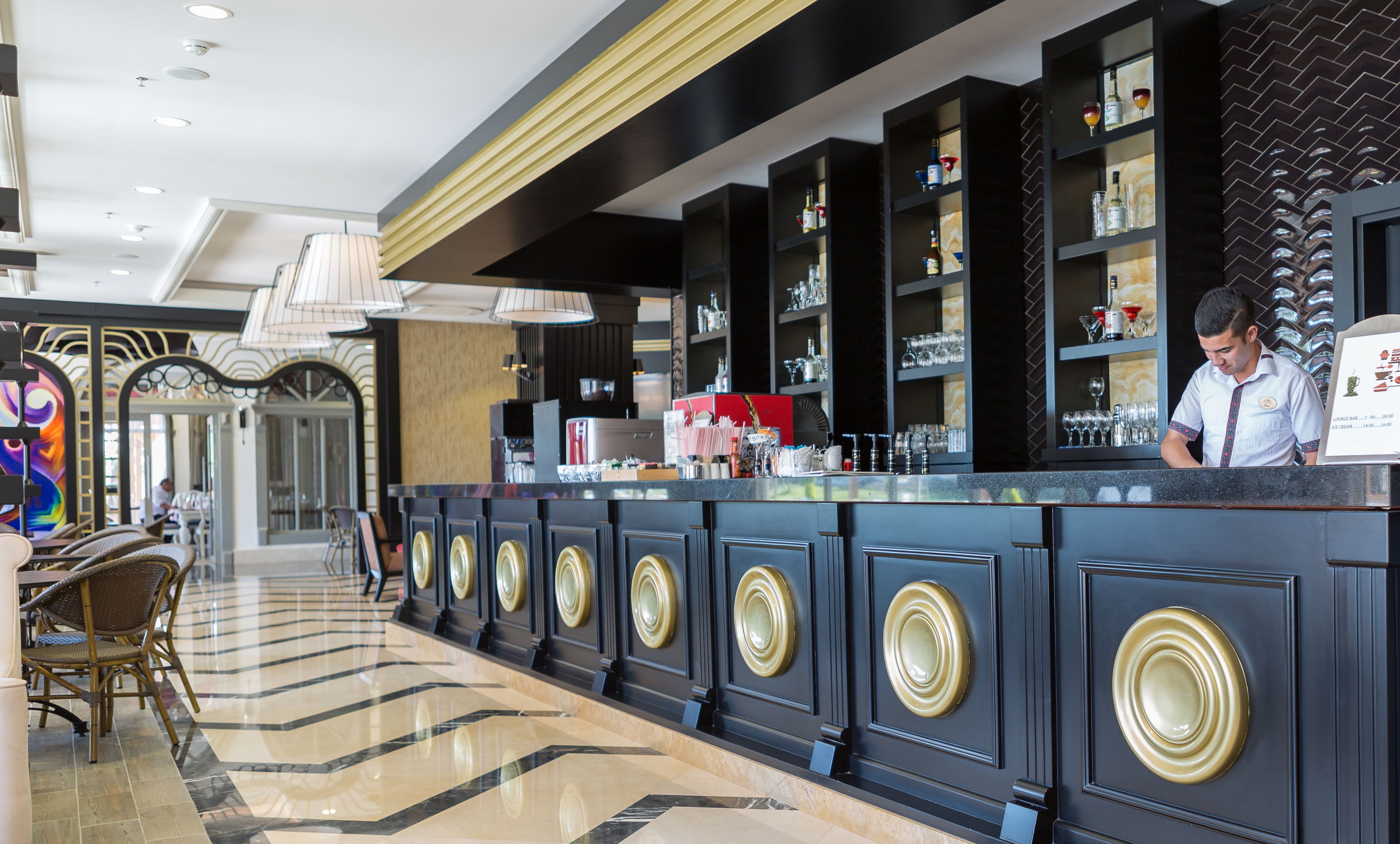 Zona de bar con mostrador, estanterías con botellas y una pizarra de menú.