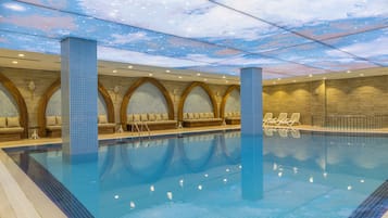 Una piscina con techo que imita un cielo estrellado, una zona de estar con bancos acolchados y una pared de azulejos con motivos florales.
