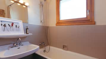 Un baño con un lavabo blanco, un espejo con iluminación, una ducha y una ventana.