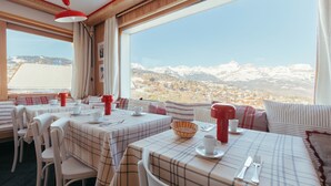 A dining area with tables set for two, featuring plaid tablecloths and red accents. - Caprice Des Neiges (Combloux)