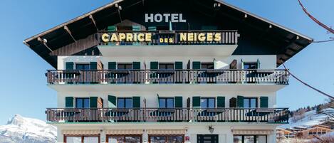 A multi-story hotel with balconies and a sign reading "HOTEL CAPRICE DES NEIGES".