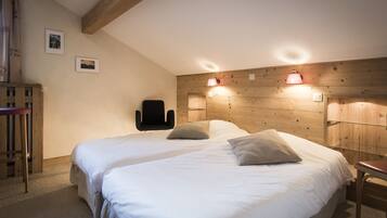 Un dormitorio con dos camas, cabeceros de madera, lámparas de pared y una silla.