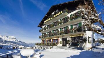 A hotel with a balcony, outdoor seating, and snow-covered surroundings.
