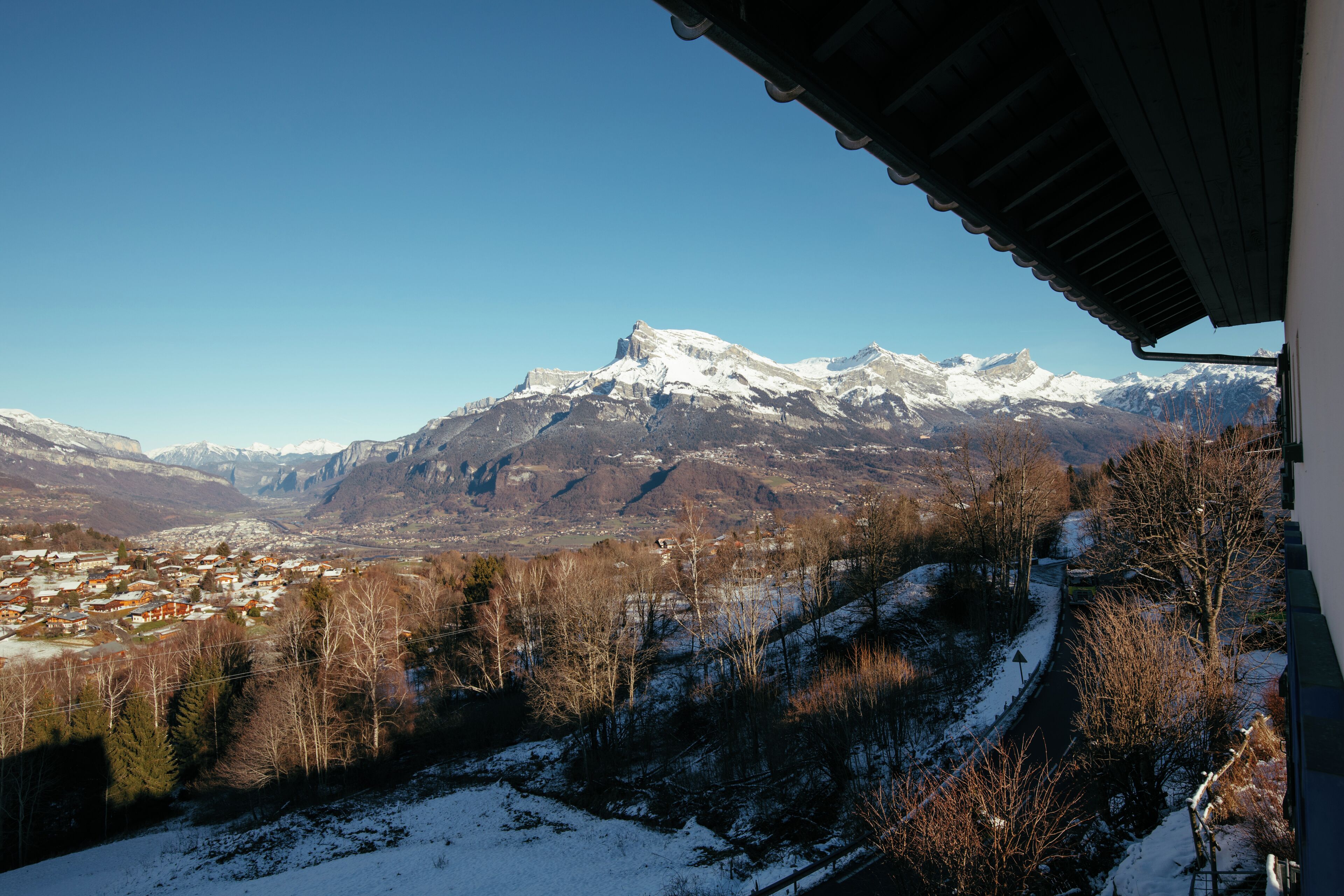 Un paysage de montagne avec des sommets enneigés et une ville en contrebas.