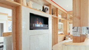 A modern interior with a fireplace, wooden shelves, and a cozy seating area. - Caprice Des Neiges (Combloux)