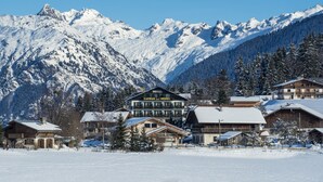 A hotel with a mountain backdrop, featuring a prominent sign and wooden architecture. - Caprice Des Neiges (Combloux)