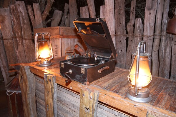 A rustic wooden table with a vintage record player and two oil lamps.