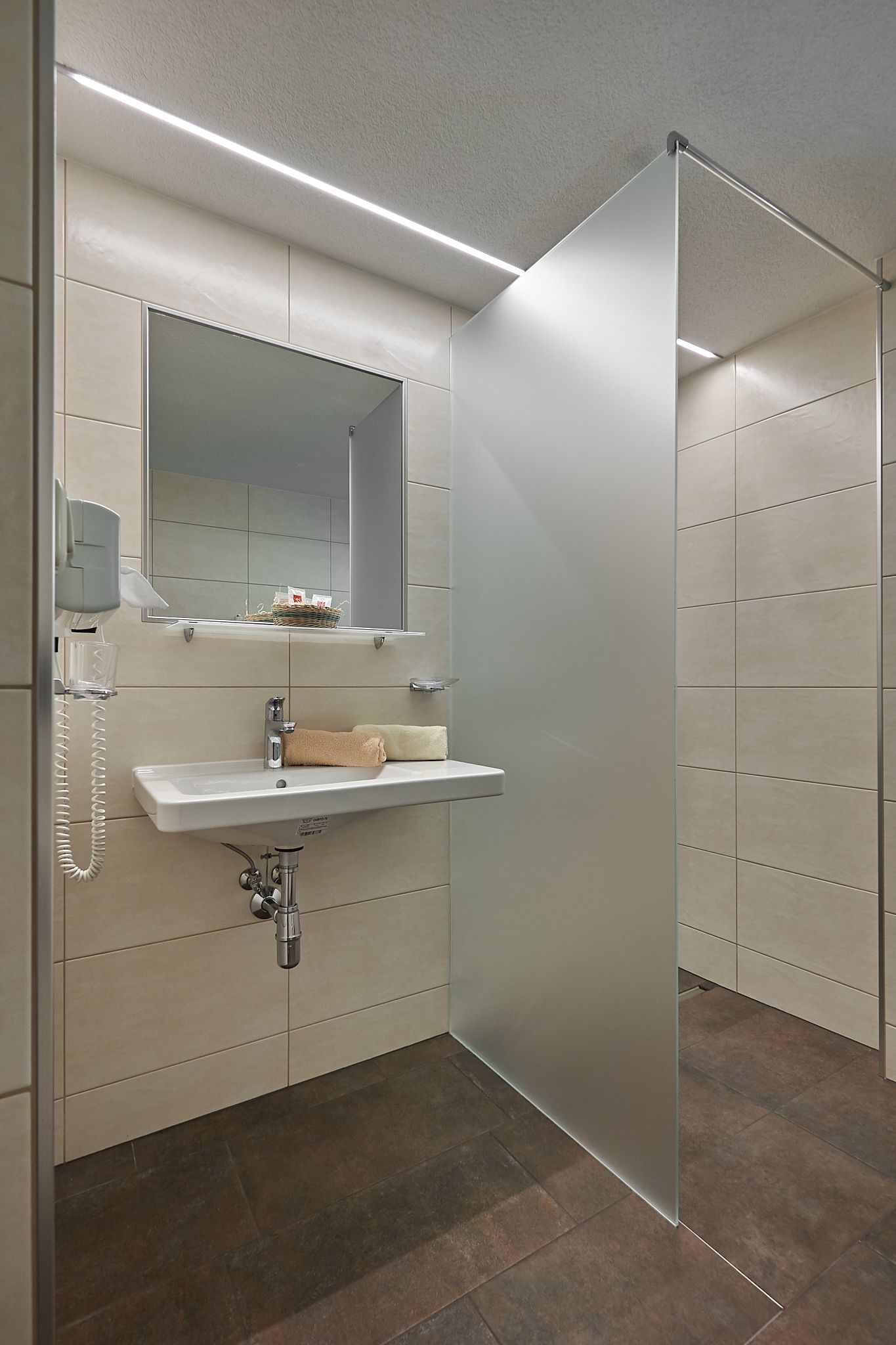 Un baño moderno con cabina de ducha de vidrio, lavabo empotrado y espejo sobre él.