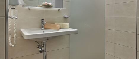 Un baño moderno con cabina de ducha de vidrio, lavabo empotrado y espejo sobre él.