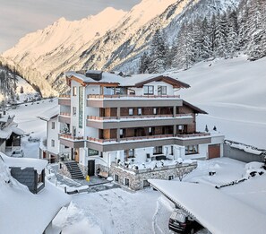 Ein mehrstöckiges Hotel mit einer Seilbahn im Hintergrund, umgeben von schneebedeckten Bergen.