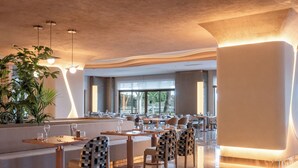 A modern restaurant with a bar area, seating, and a large plant. - Adalya Bliss - All inclusive (Manavgat)