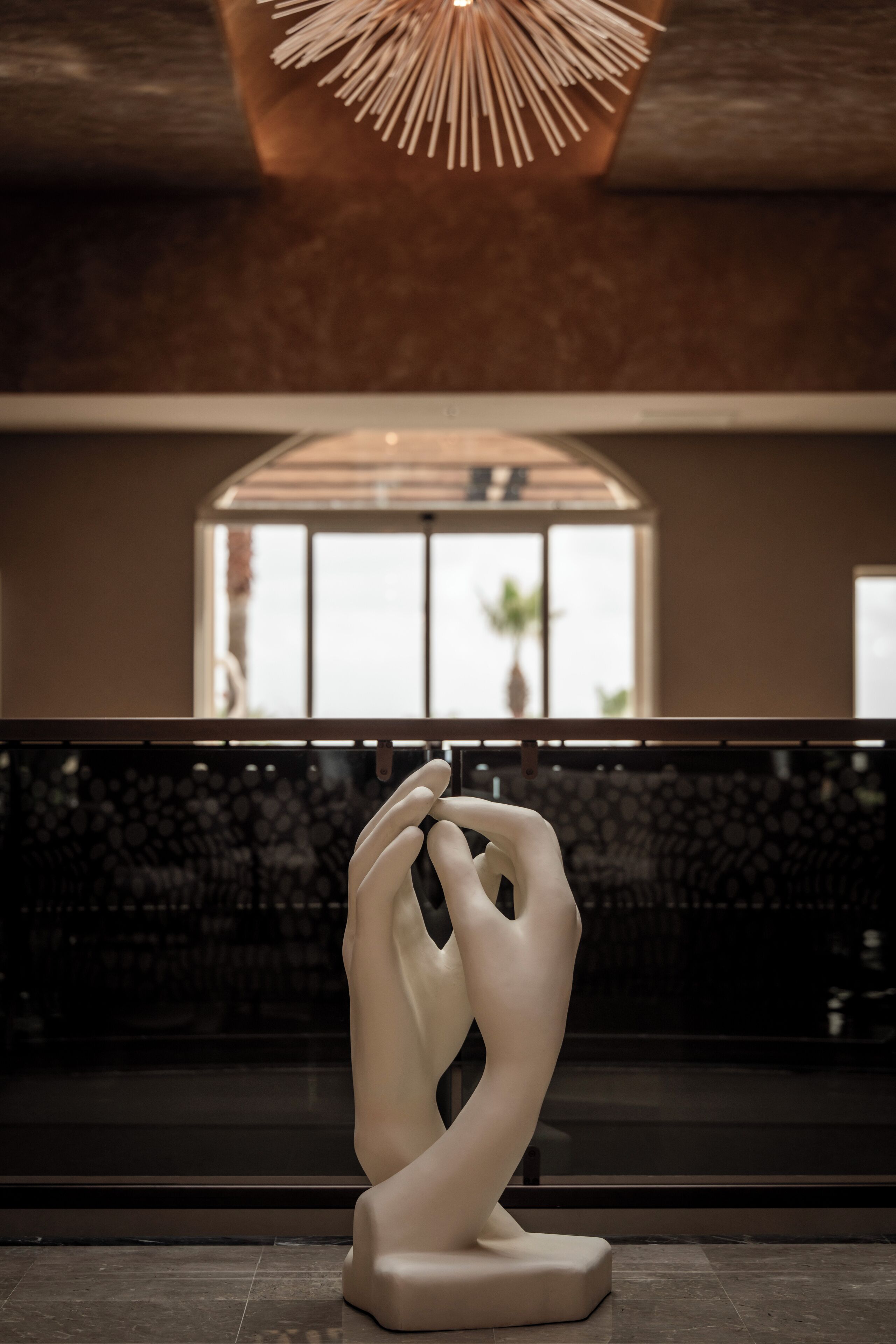 A modern interior with a sculptural centerpiece, a large window, and a patterned wall.