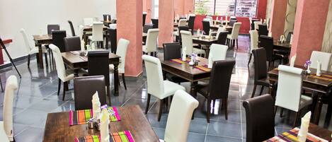 A spacious restaurant with multiple dining tables and chairs, arranged in a modern layout.