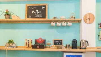 Un rincón con café, una pizarra, un reloj y un refrigerador lleno de bebidas.