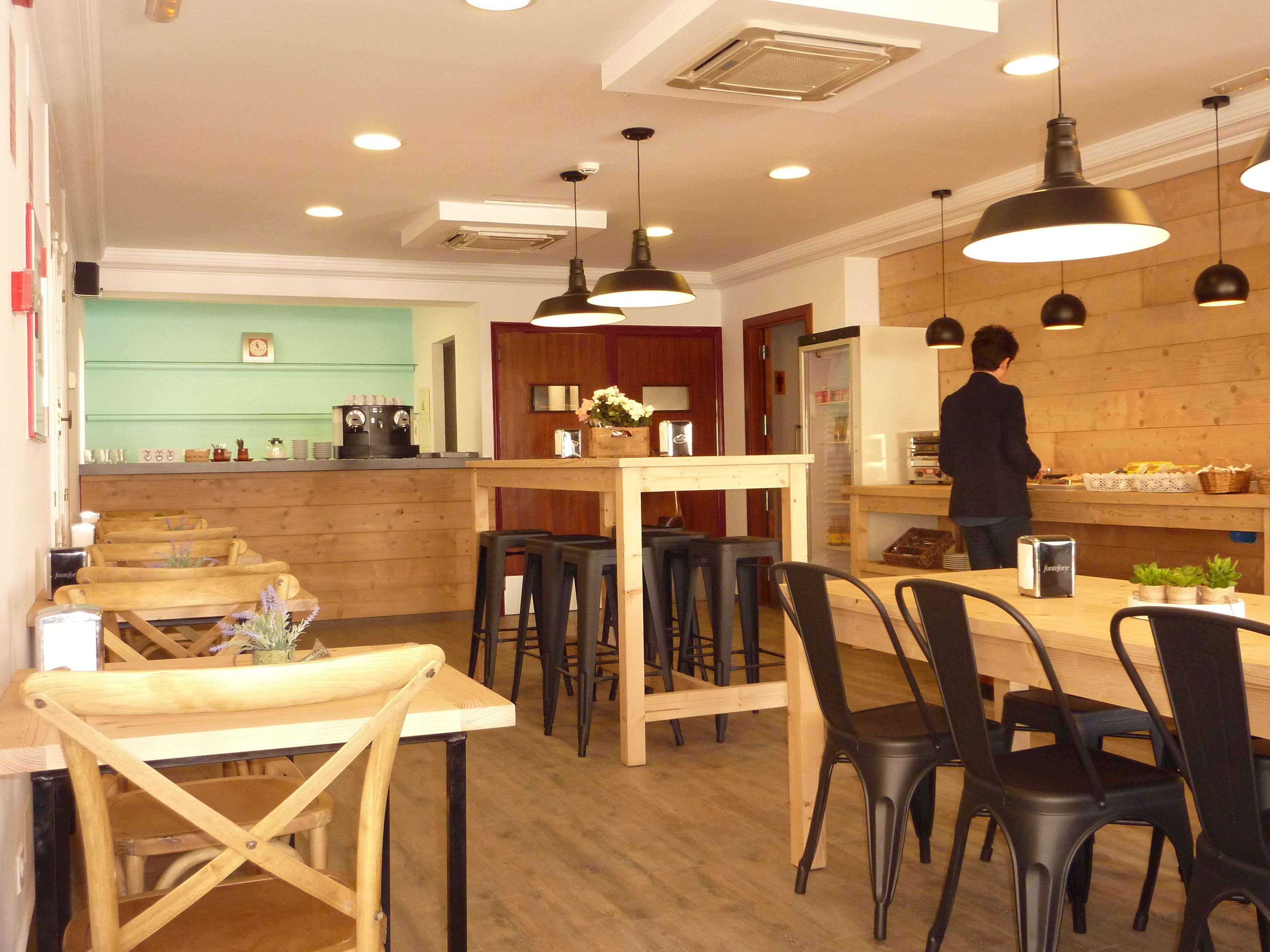 Un café acogedor con muebles de madera, una barra y una persona preparando comida.