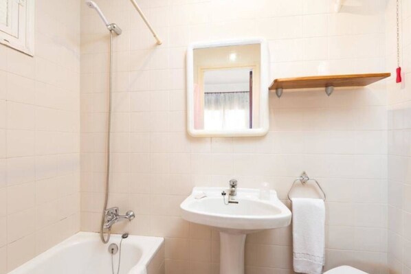 A bathroom with a bathtub, a sink, a mirror, and a towel rack. - Hostal Jume - Urban Rooms (Mahón)