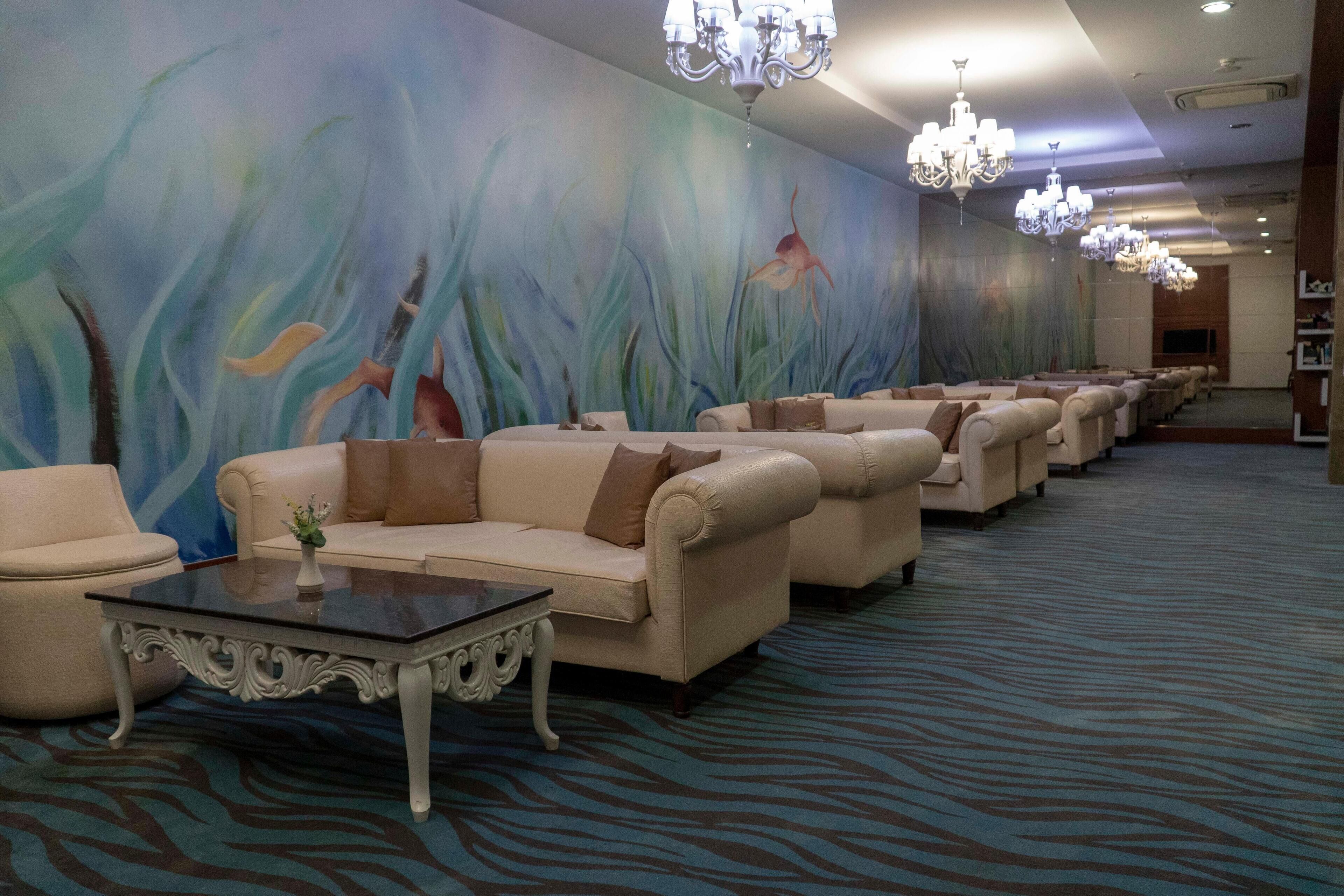 A hotel lobby with a row of sofas, a coffee table, and a large mural on the wall.