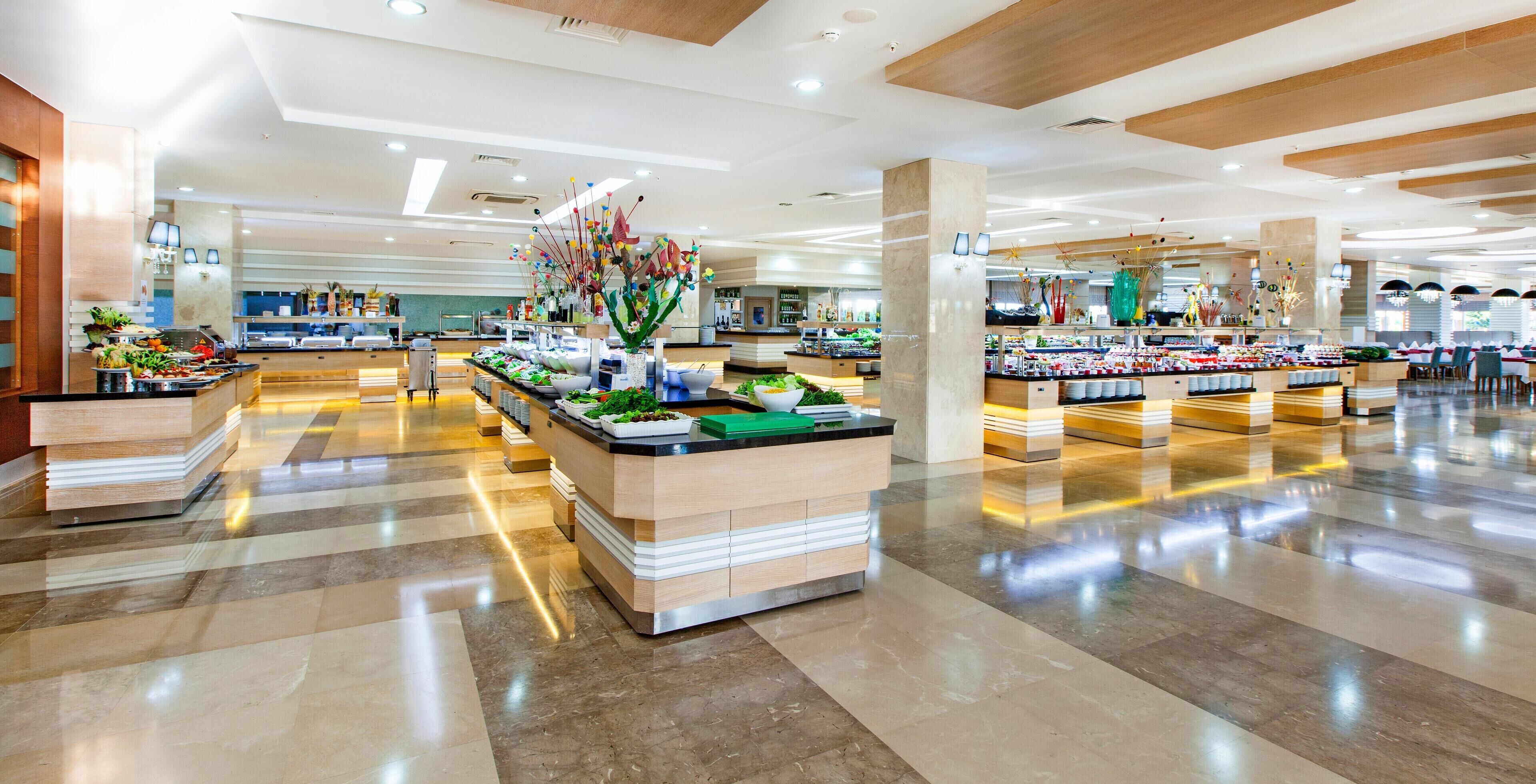 A spacious hotel lobby with a central reception desk, multiple seating areas, and a variety of food and beverage stations.