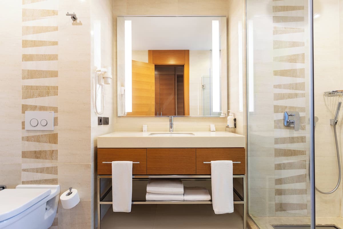 Un baño moderno con lavamanos, espejo y ducha.