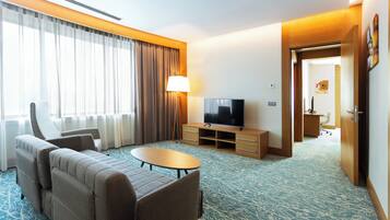 A hotel room with a sofa, a TV, a lamp, and a desk.