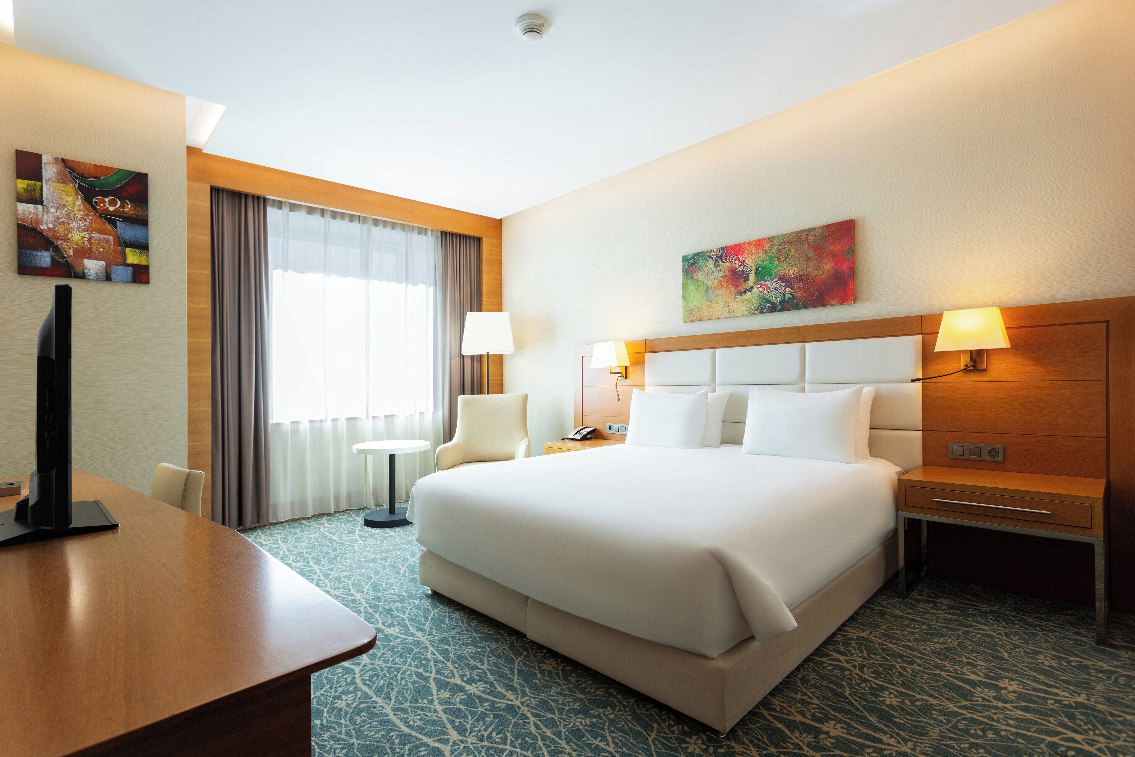 Une chambre d’hôtel avec un grand lit, des tables de chevet, un bureau et une chaise.