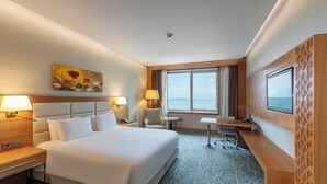 A hotel room with a large bed, a desk, a chair, a TV, and a painting on the wall. - Holiday Inn Baku by IHG (Baku)