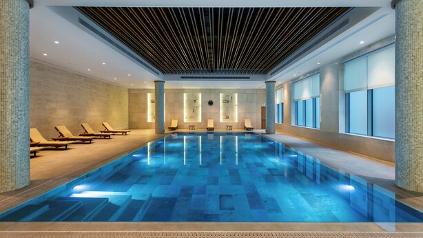 A large indoor swimming pool with lounge chairs and a modern ceiling design. - Holiday Inn Baku by IHG (Baku)