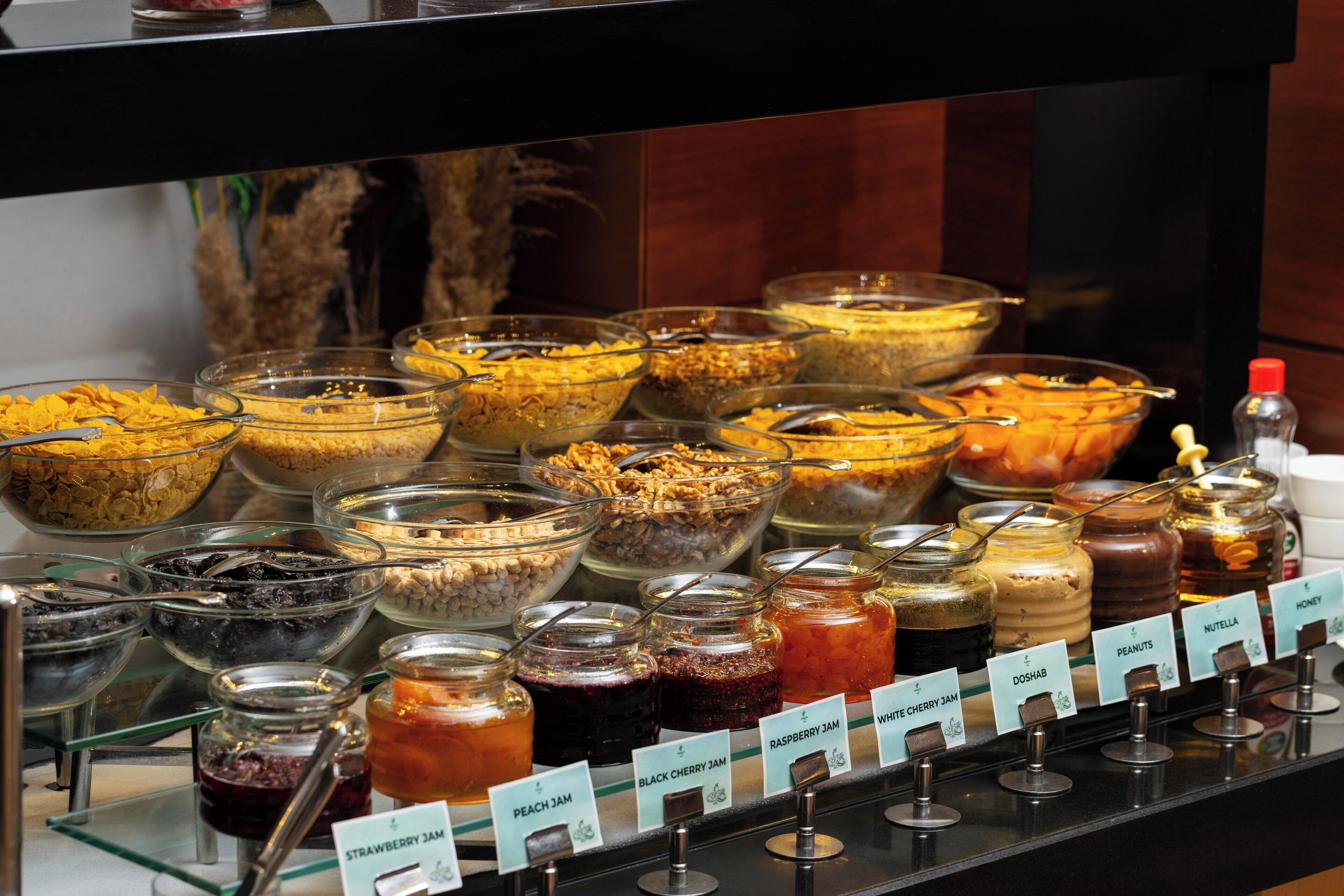 Een buffet met verschillende potten jam en een bordje waarop de soorten jam staan aangegeven.