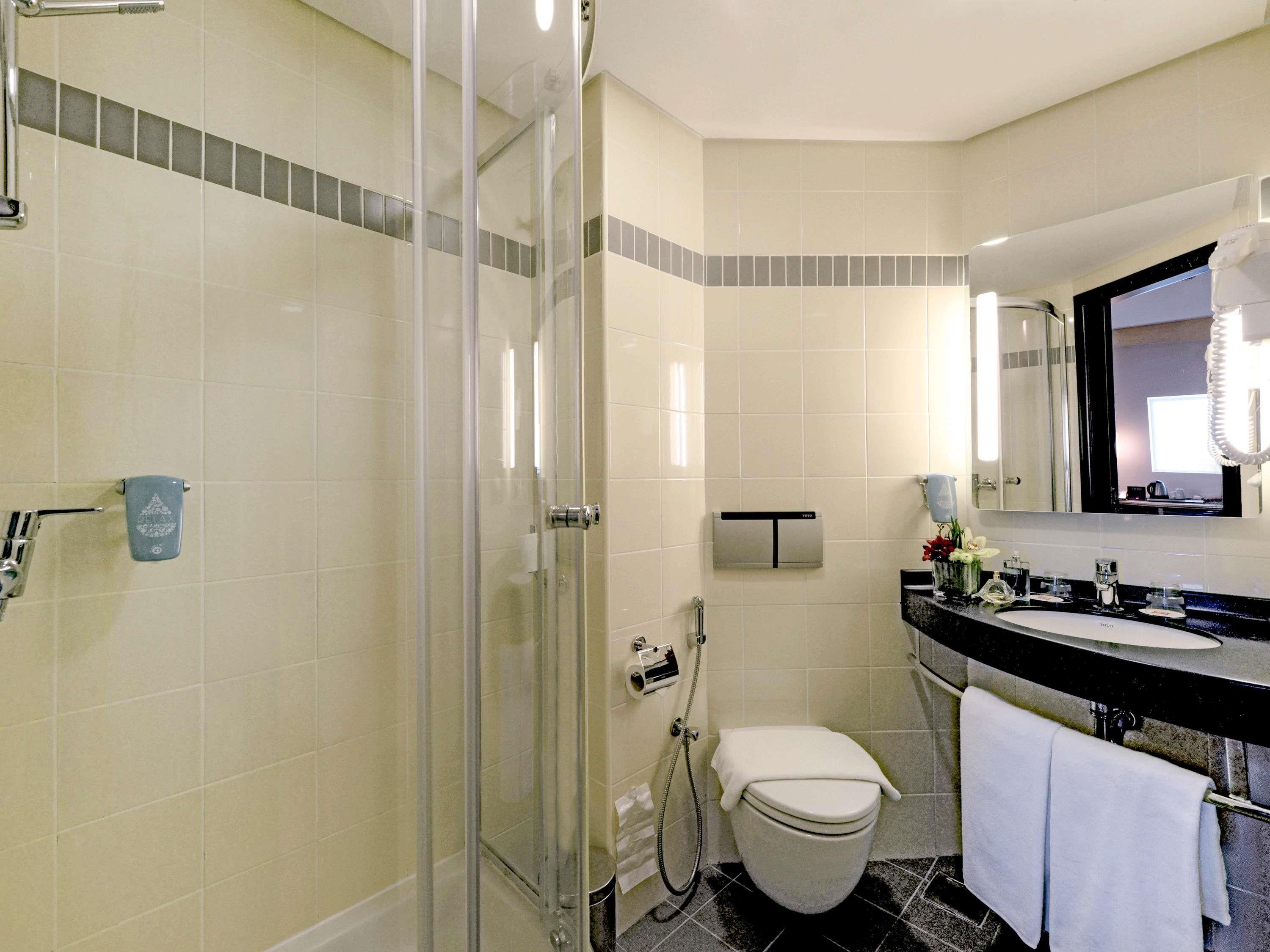 Une salle de bain avec une douche à parois de verre, des toilettes, un lavabo avec un miroir et un porte-serviettes.