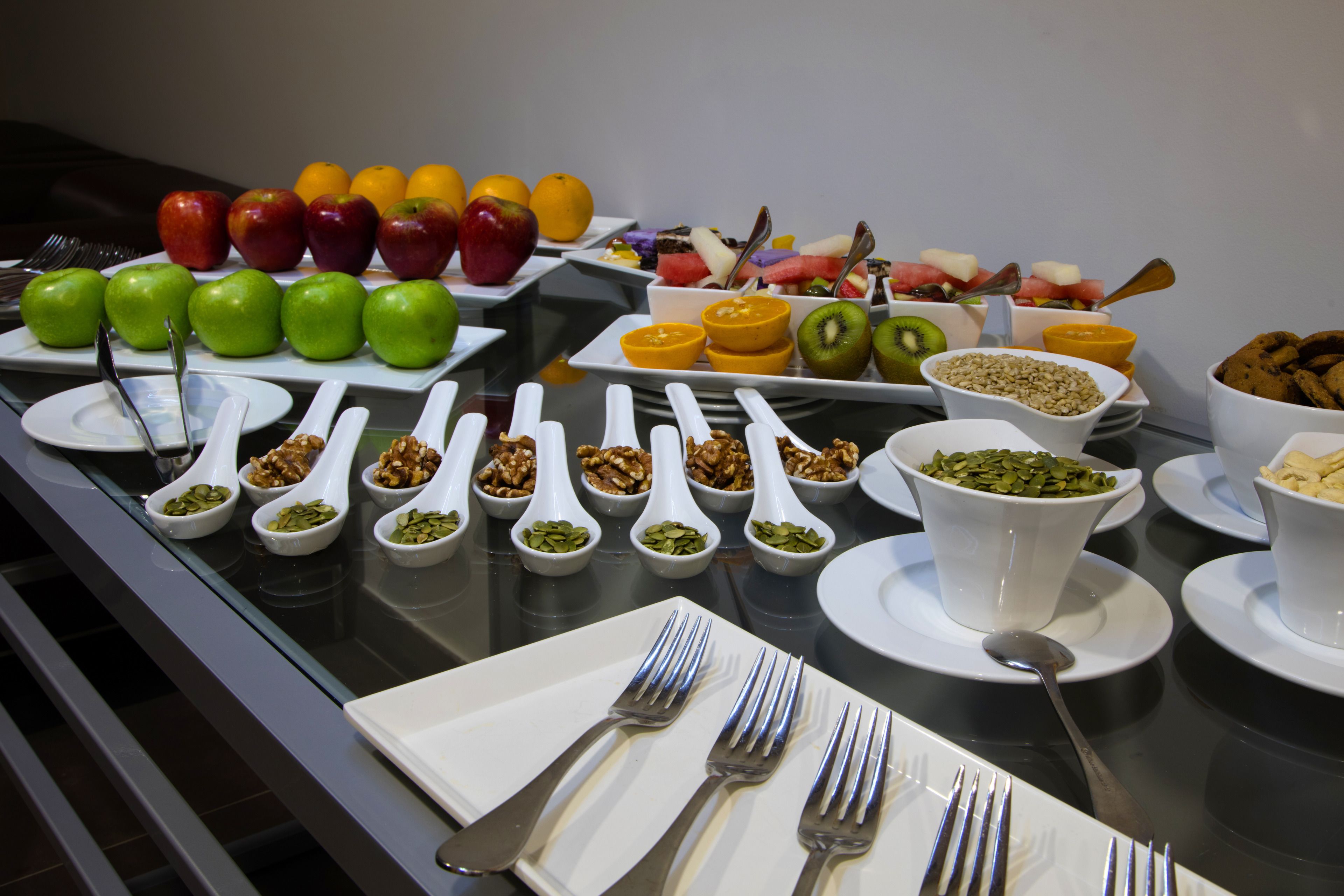 Een ontbijtbuffet met verschillende soorten fruit, noten en granola.