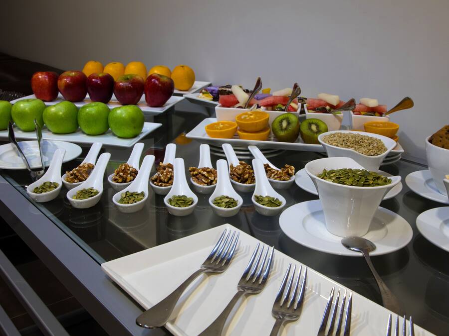 Een ontbijtbuffet met verschillende soorten fruit, noten en granola.