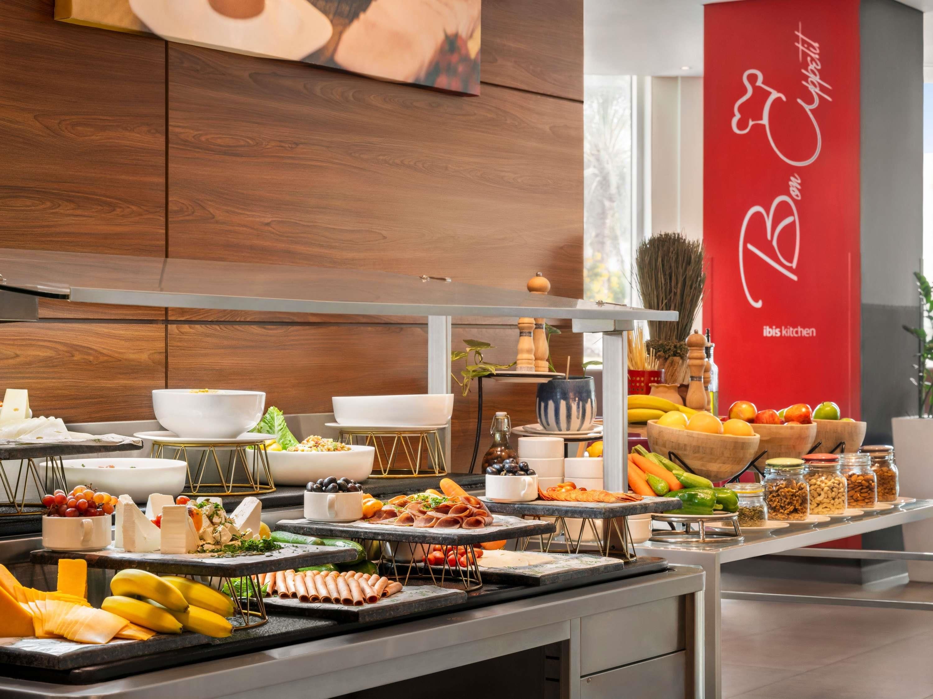 A buffet setup with various food items and a red banner with the logo "ibis kitchen".