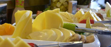 A buffet with various food items including cheese, fruits, and vegetables.
